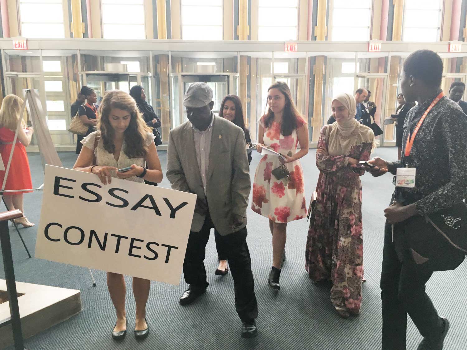 Photo: young people in lobby with Essay Contest sign